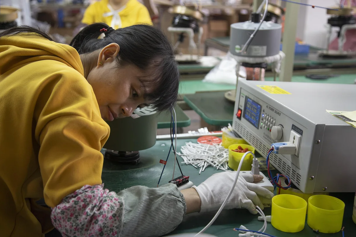 Technician testing an electrical component at a production station